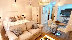 Un salon moderne comprenant un canapé, une table basse et un coin repas avec une table et des chaises en verre.