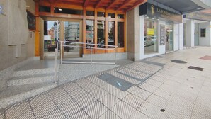 Une entrée d’immeuble avec une façade en bois, une porte en verre et une rampe menant à l’entrée.