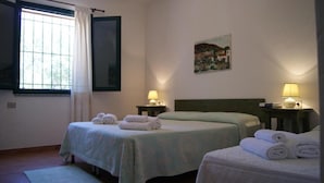 A hotel room with two beds, a window with curtains, a painting on the wall, and two bedside lamps.