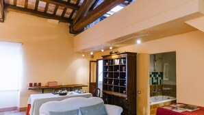 A cozy room with a white sofa, a wooden bookshelf, a small table with a red tablecloth, and a shower area. - Much loved by many: FIENILE, in the historic center, 7 km from the sea (Fermo)