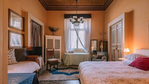 A bedroom with two beds, a chandelier, a window with curtains, and a small table with a lamp. - Live in PALAZZO, historic center, 7 km from the sea (Fermo)