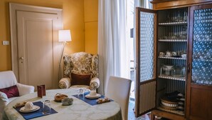 A hotel room with a dining area, a floral armchair, a cabinet with glass doors, and a bed with a blue cover. - Live in PALAZZO, historic center, 7 km from the sea (Fermo)