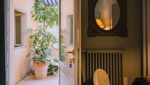 Une porte donnant sur un petit espace extérieur agrémenté d’une plante en pot et d’une fenêtre.
