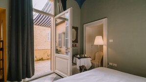 Une chambre d’hôtel avec un lit, une table avec une lampe et une porte ouverte donnant sur un balcon.