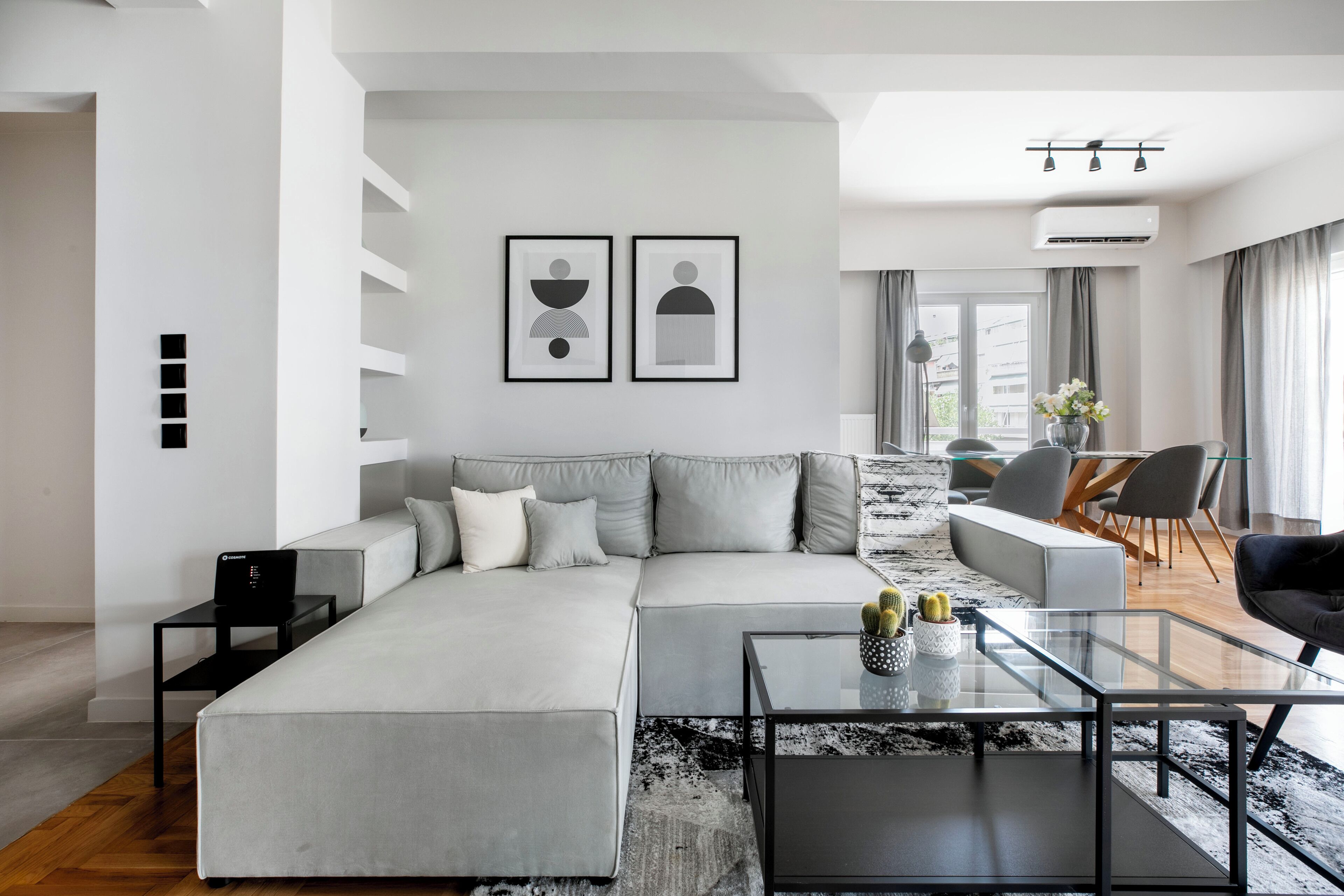 Una sala de estar moderna con un sofá modular, una mesa de centro de vidrio y un comedor con sillas y una mesa.