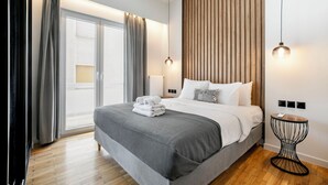 A modern hotel room with a large bed, a wooden slat wall, and a small round table. - Astoria -Luxury 2-BR Apartment in Athens (Athens)