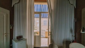 Habitación de hotel con vista a un patio, un escritorio pequeño con lámpara y una silla.