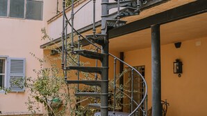 Una escalera de caracol que conduce a un piso superior de un edificio con fachada color crema.