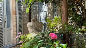 A garden area with a bench, potted plants, and a stone structure. - House with a garden, downtown, 7 km from the beaches. (Fermo)