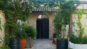 A brick pathway leading to a black door with a tiled roof above. - House with a garden, downtown, 7 km from the beaches. (Fermo)