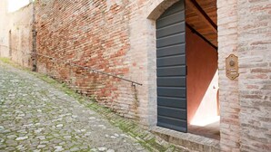 A brick building with a cobblestone path and a large arched doorway. - House with a garden, downtown, 7 km from the beaches. (Fermo)