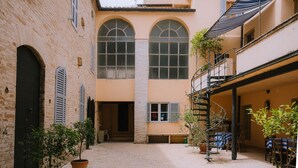 A courtyard with a brick floor, potted plants, and a spiral staircase leading to an upper level. - PALAZZO to live in, historic center, gardens terraces, 7 km from the sea (Fermo)
