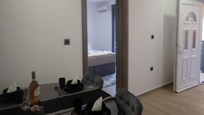 A hotel room with a dining area, a bed, and a door.