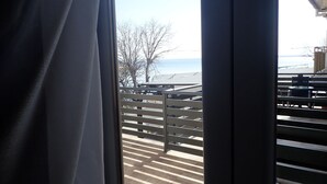 A view from a window with a view of a deck area, including a railing and outdoor seating.