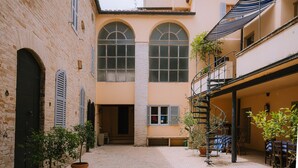 Ein Innenhof mit Backsteinmauern, Rundbogenfenstern und Topfpflanzen.