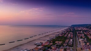 Eine Küstenstadtlandschaft mit Strand, Wohnhäusern und einem klaren Himmel bei Sonnenuntergang.