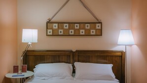 A hotel room with a wooden headboard, two white pillows, a bedside table with a lamp, and a wall-mounted picture frame. - Room in PALACE, in the historic center (Fermo)