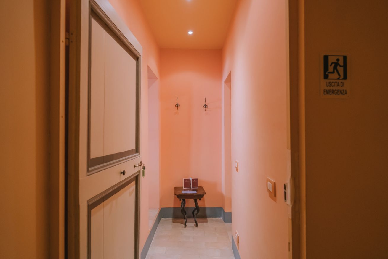 Ein Korridor mit Tisch, Stühlen, einer Tür und einem Notausgangsschild.