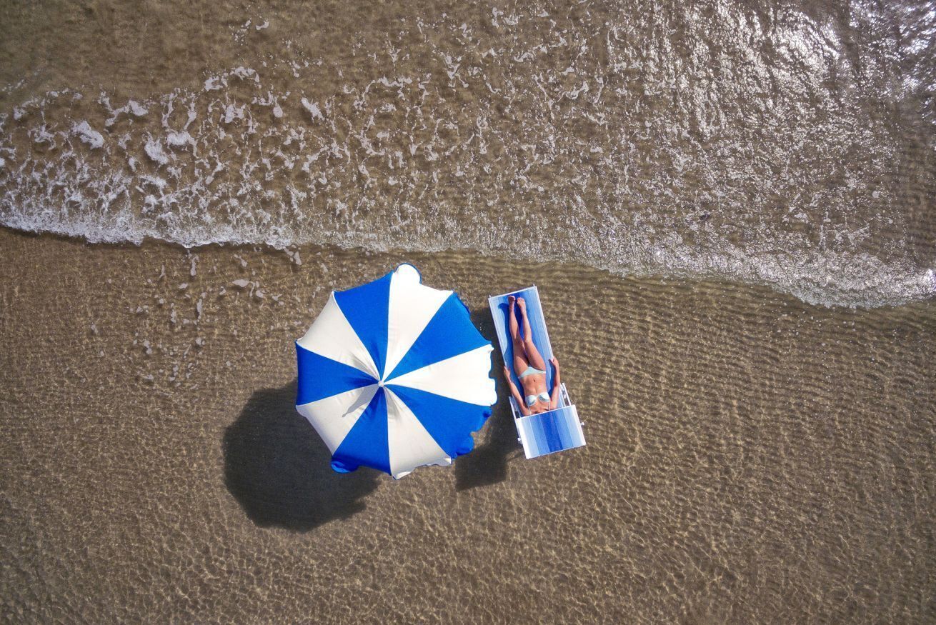 Una spiaggia con un ombrellone a righe e una sedia a sdraio.