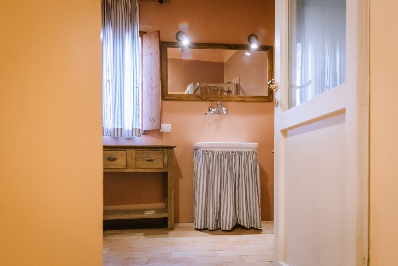 Een badkamer met een houten wastafelmeubel, een wastafel en een spiegel.