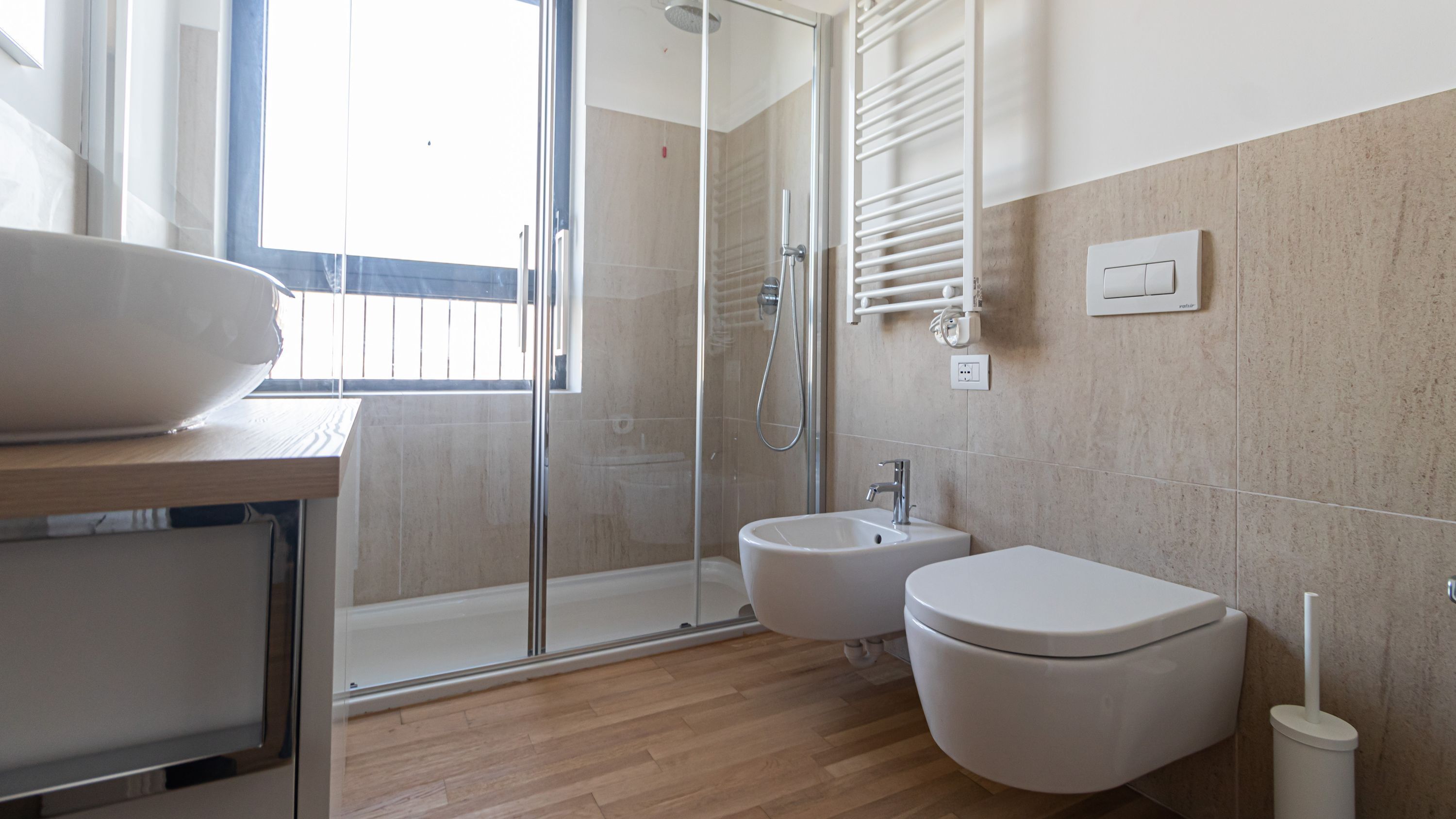 A modern bathroom with a glass shower enclosure, a sink, and a toilet.