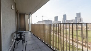 A balcony with a table and chairs, a view of a cityscape with modern buildings and construction cranes, and a fenced grassy area. - Italianway Comfort - Pichi 19 (Milan)