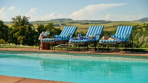 Ein Poolbereich mit Liegestühlen und Blick auf sanfte Hügel.