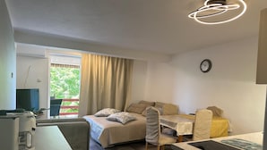 A compact room with a bed, a dining table, a kitchenette, and a TV. - Apartment Matkovic 3 (Jadranovo)