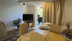 A living room with a sofa, a television, and a dining area with a table and chairs. - Apartment Matkovic 3 (Jadranovo)