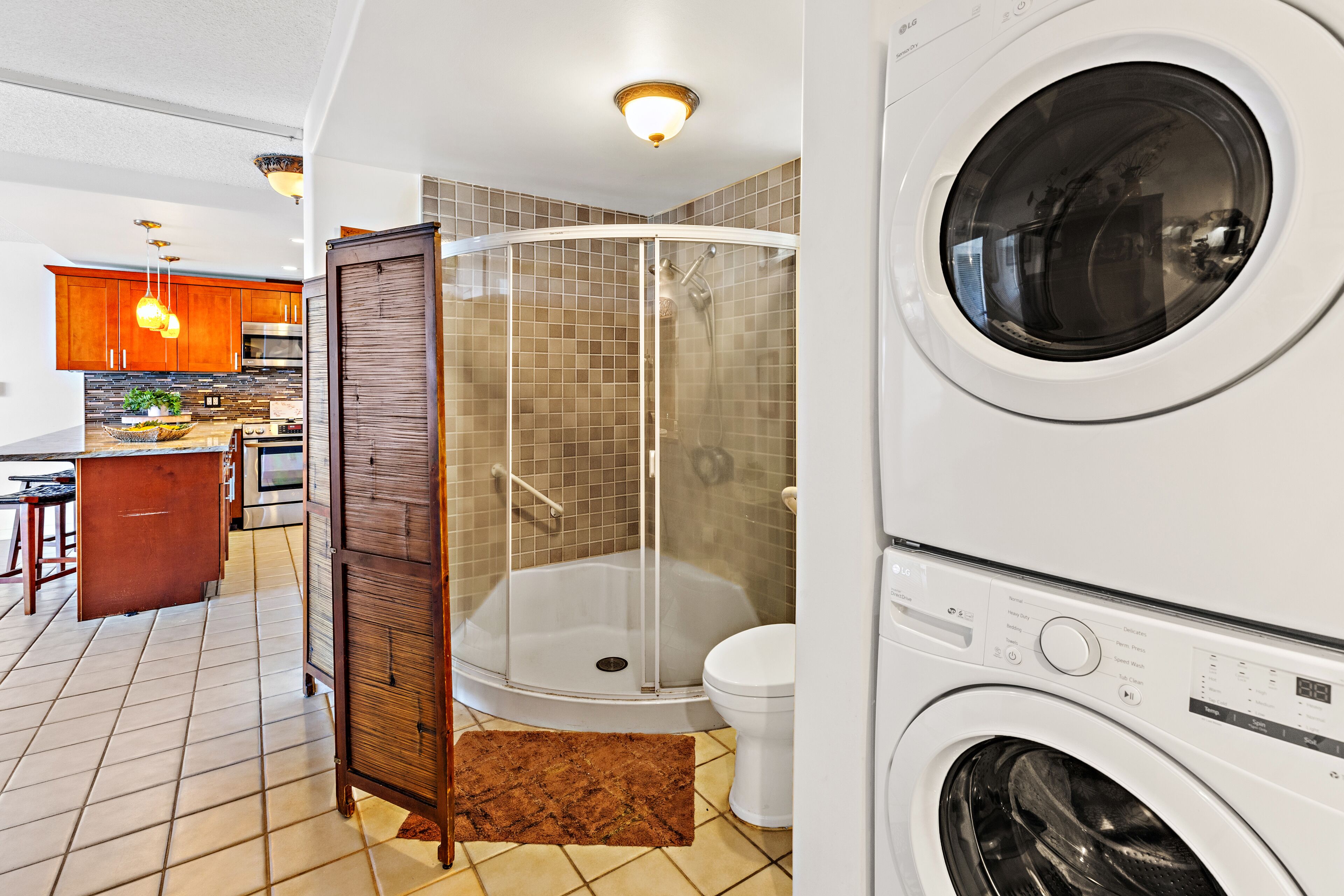 Une salle de bain moderne avec une douche à parois de verre, des toilettes blanches et un lave-linge à chargement frontal.