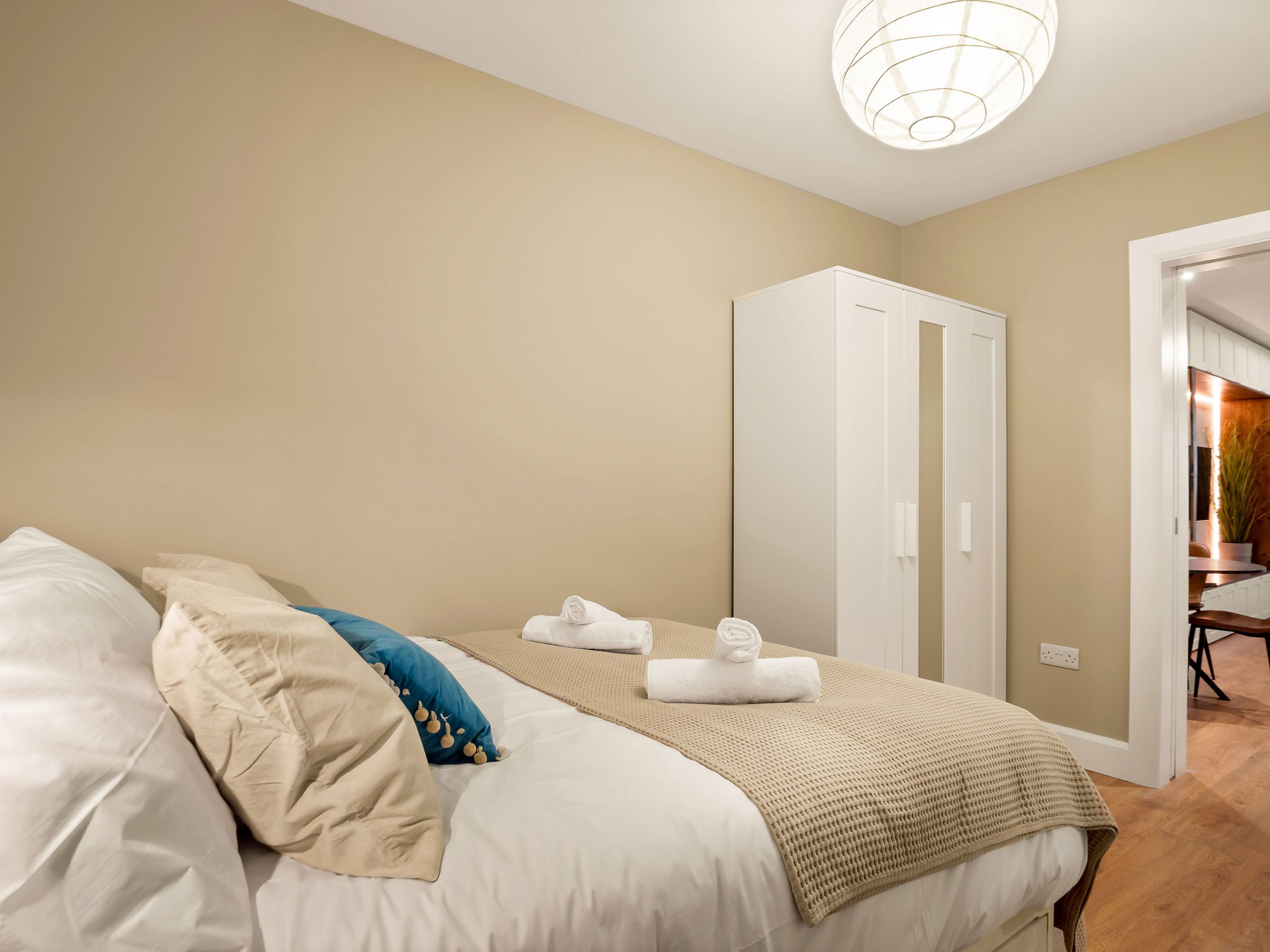 Une chambre à coucher avec un lit, deux armoires blanches, un mur beige et une porte donnant sur une salle de bain.