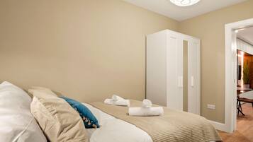 Une chambre à coucher avec un lit, deux armoires blanches, un mur beige et une porte donnant sur une salle de bain.