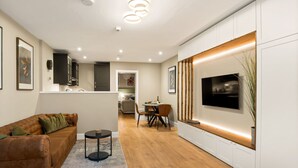 Un salon moderne avec un canapé en cuir marron, une table basse ronde et un téléviseur fixé sur un mur décoratif en bois.