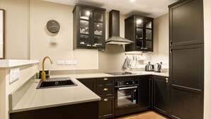 Une cuisine moderne avec des meubles de rangement aux couleurs sombres, un four encastré et un évier en acier inoxydable.