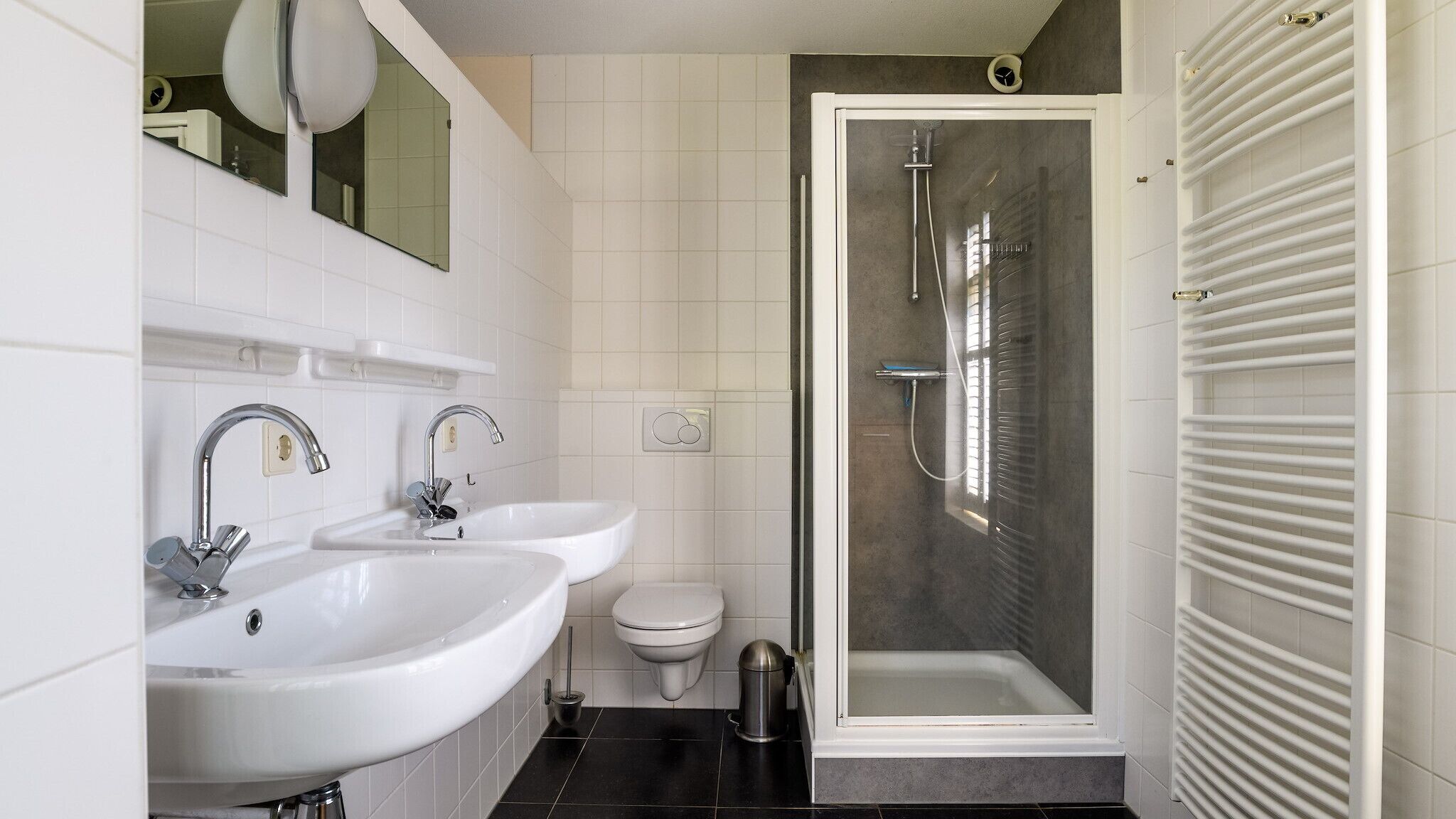 Une salle de bain moderne avec deux lavabos, des toilettes et une douche à l’italienne.