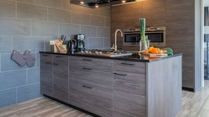 Una cocina moderna con una isla central, armarios de madera oscura, una campana extractora de acero inoxidable y un horno empotrado.