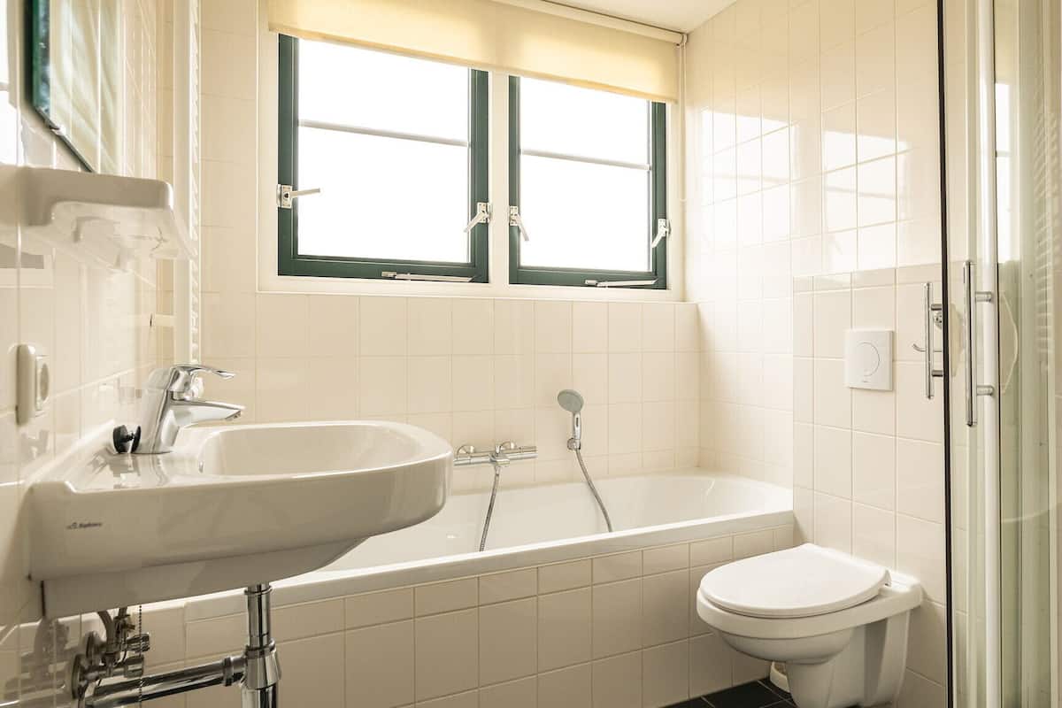 A bathroom with a bathtub, sink, toilet, and a glass shower enclosure.