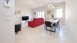 Un salon moderne avec un canapé rouge, un téléviseur à écran plat et un coin repas comprenant une table et des chaises.