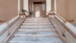 Un escalier en marbre avec des rampes en laiton menant à une porte située en haut.