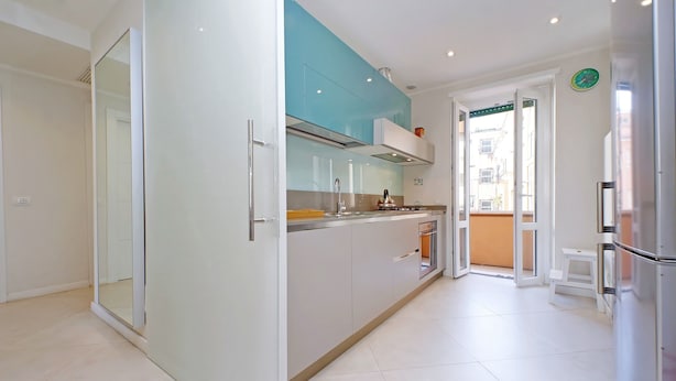 Une cuisine moderne avec une porte en verre, des armoires blanches et un pare-feu turquoise.