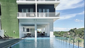 Une piscine offrant une vue dégagée sur les environs, notamment sur un immeuble doté de balcons et d’un espace de détente extérieur.
