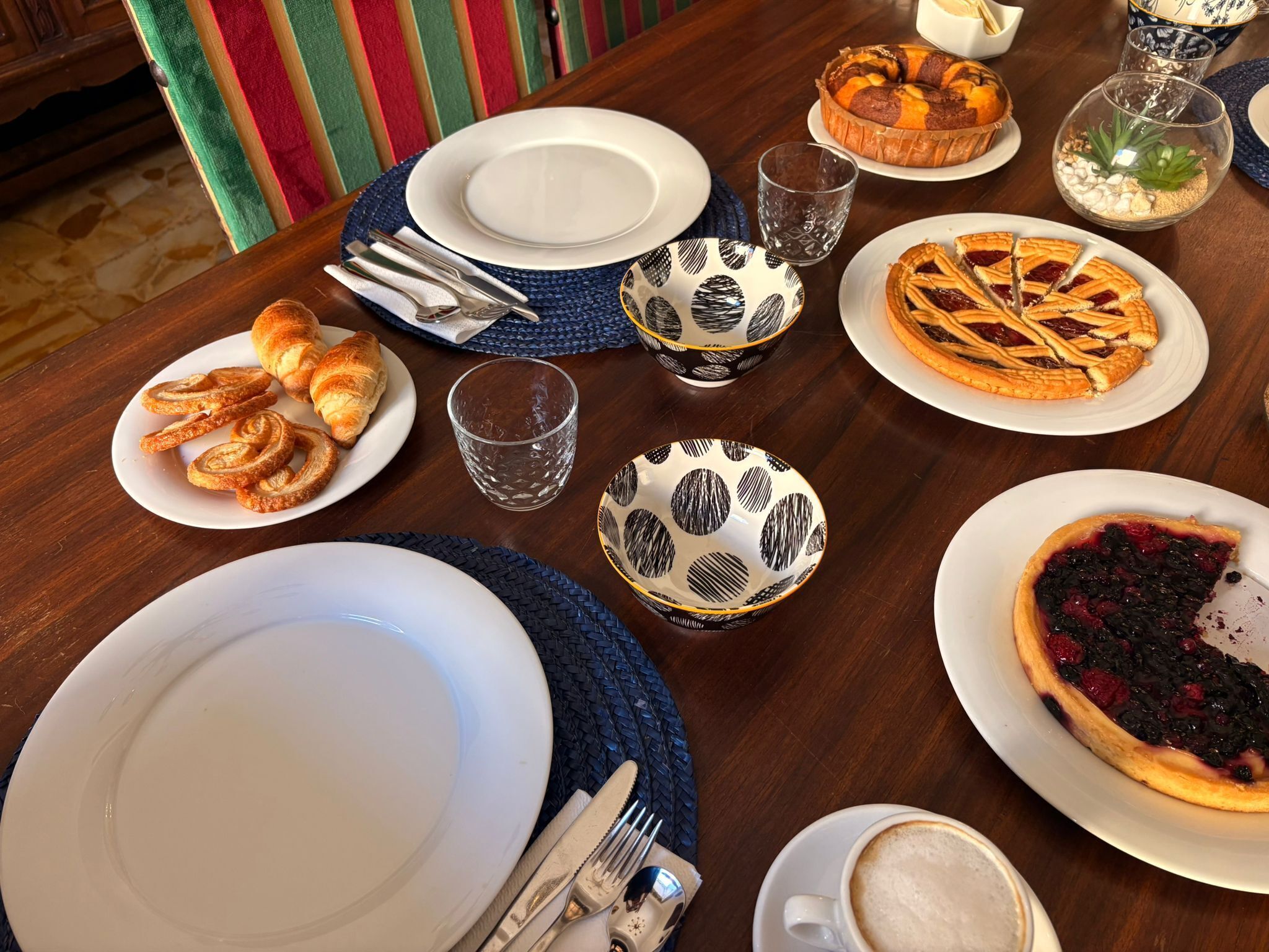 A dining table set with plates, cutlery, glasses, and various desserts.
