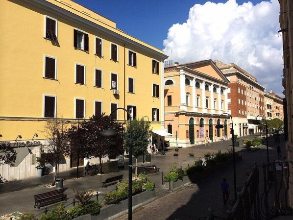 A street view with yellow and red buildings, benches, and a clear sky.