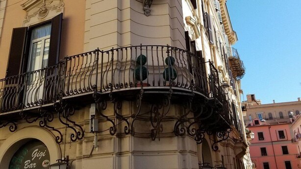 A corner building with a balcony, a statue, and a sign for 'Gigi Bar'. - Palazzo Alibrandi (Civitavecchia)