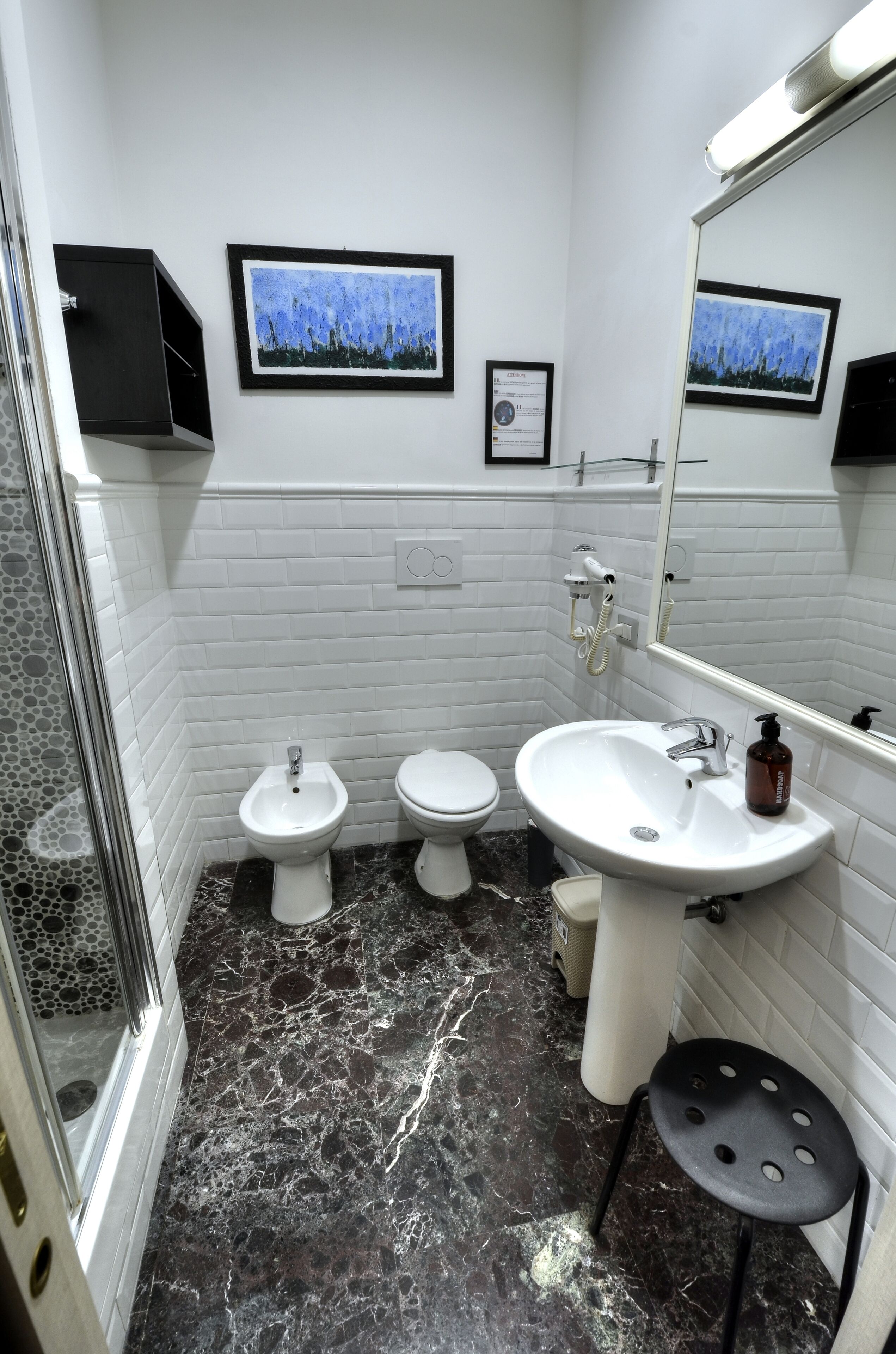 Un baño con azulejos blancos tipo metro, un lavamanos blanco, un bidé, un inodoro y una zona de ducha.