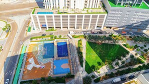 An aerial view of a modern urban area with a large building, a basketball court, and a green park.