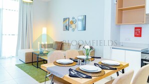 Ett modernt vardagsrum med en matplats, en soffa, ett soffbord och en köksdel med ett skåp och en skylt som visar brandsäkerhetsföreskrifter.