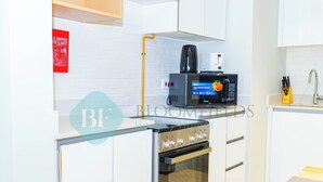 Ett modernt kök med en inbyggd ugn, mikrovågsugn och en kaffebryggare på bänkskivan.