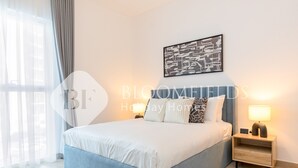 Een moderne slaapkamer met een groot bed, nachtkastjes en een kunstwerk aan de muur.