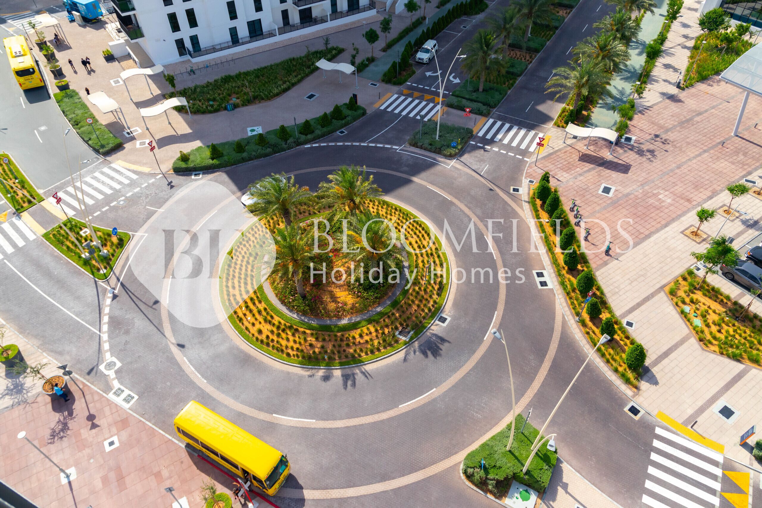 Vue aérienne d’un rond-point doté d’un espace paysager central, entouré de routes et d’immeubles.